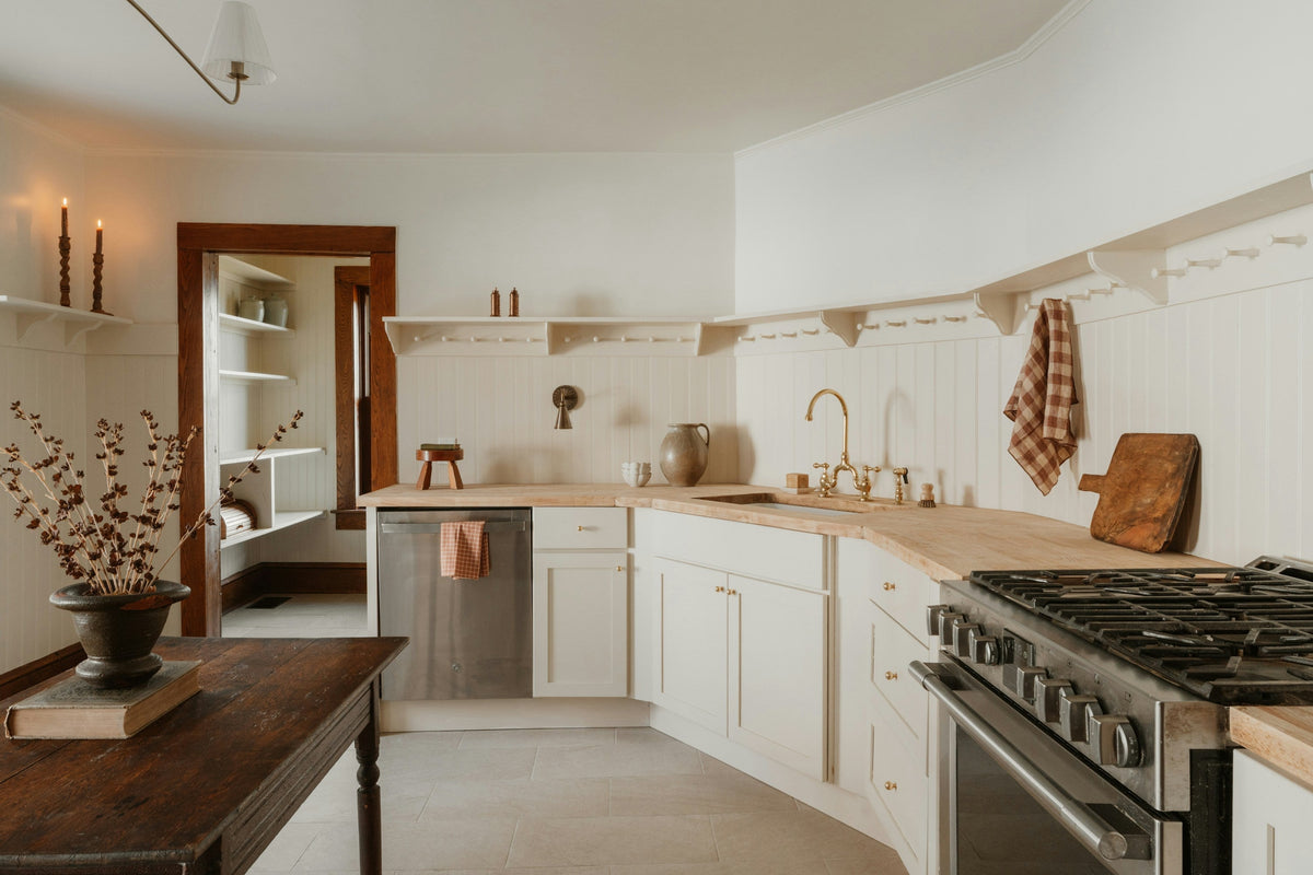 A farmhouse kitchen in daylight, plain surfaces and open shelving